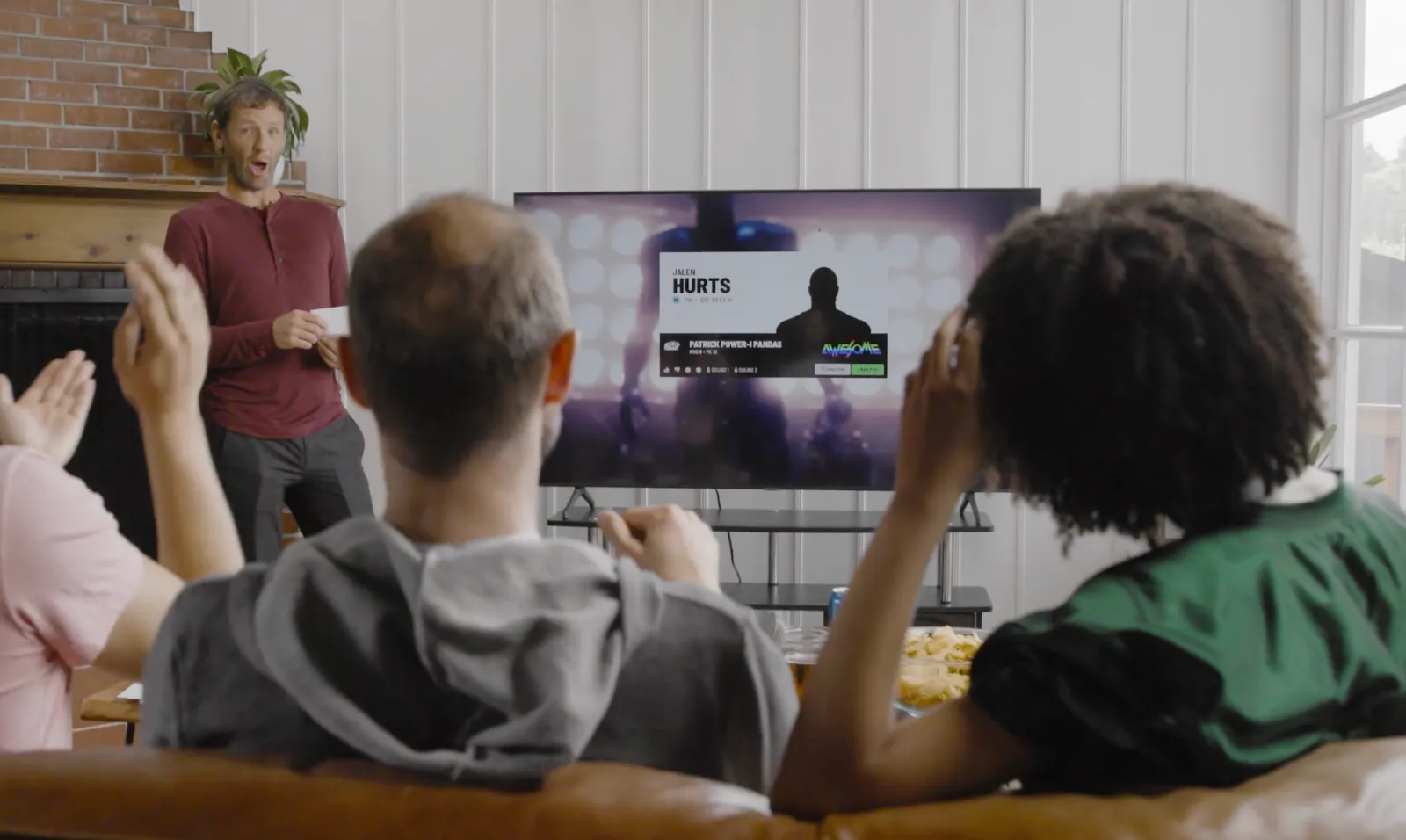 A fantasy football league watching the FanDraft draft board on a living-room TV